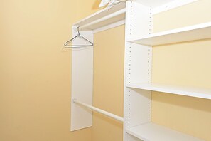A white metal wardrobe with multiple shelves and a hanging rod.