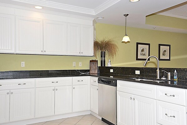 A kitchen with white cabinetry, a black countertop, and a green wall.
