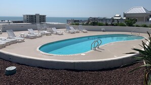 En pool på taket med solstolar, en hoppställning och utsikt över havet.