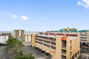 A multi-story hotel with a parking lot and a view of the ocean.