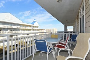 A balcony with a table and chairs, overlooking a hotel building with a blue roof.