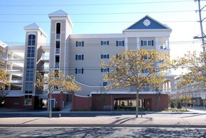 A multi-story hotel with a central tower, a covered entrance, and a parking area.
