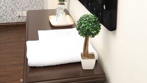 A bathroom with a dark brown vanity, a white towel, a small potted plant, and a mirror with a black frame. - The Westin Suites Hotel (Lahore)