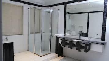 A modern bathroom with a glass shower enclosure, a black and white tiled vanity, and a large mirror.