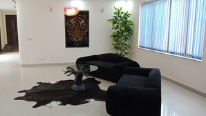 A modern living room with a black sofa set, a glass coffee table, and a large potted plant. - The Westin Suites Hotel (Lahore)