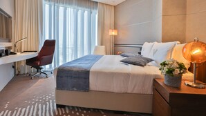 A modern hotel room with a large bed, a desk, and a chair.