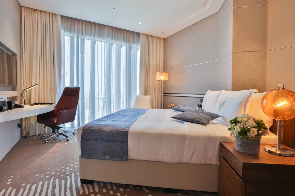 A modern hotel room with a large bed, a desk, and a chair.