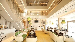 A spacious lobby with a reception desk, multiple seating areas, and a high ceiling with modern lighting. - VIP Hotel (Doha)