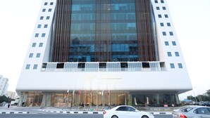 A modern hotel building with a prominent entrance and multiple flags.