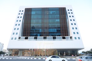 A modern hotel building with a prominent entrance and multiple flags.
