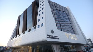 A modern hotel with a prominent 'Barjees Restaurant' sign, large windows, and a distinctive architectural design. - VIP Hotel (Doha)