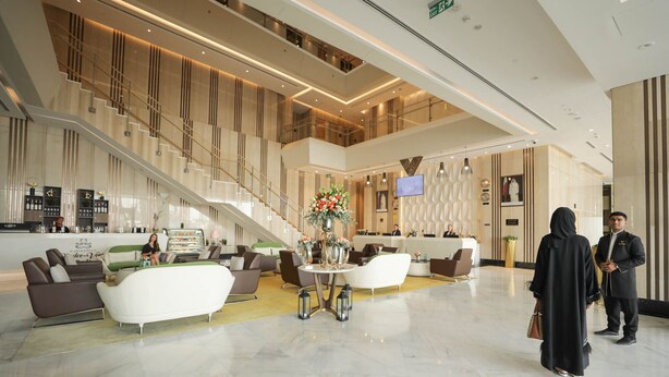 A spacious lobby with a high ceiling, a staircase, and a reception desk. - VIP Hotel (Doha)