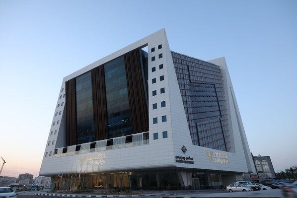 A modern hotel with a unique angular design, featuring large glass windows and a prominent entrance.