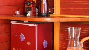 A compact kitchenette with a red refrigerator, a coffee maker, and a blender on a wooden countertop. - Poz Lagon (Saint-Paul)