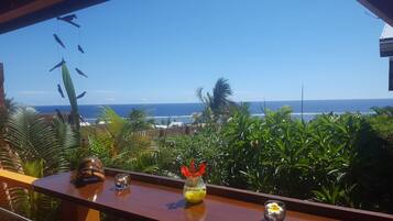 Enjoy the ocean view from this balcony, surrounded by lush greenery and tropical plants.