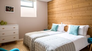 A bedroom with two beds, a dresser, a window, and a wooden wall. - Central Duplex Apartment with Large Terrace (Chamonix-Mont-Blanc)