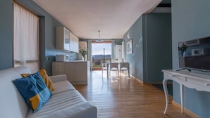 Ein modernes Wohnzimmer mit einem weißen Sofa, einem Fernseher und einem Essbereich mit Tisch und Stühlen.