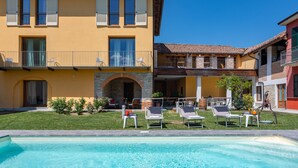 Ein gelbes Gebäude mit Swimmingpool, Außenbereich und einem steinernen Bogen.