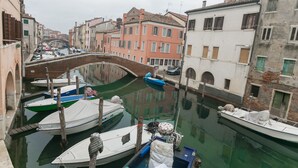 A canal with boats docked, a bridge, and buildings along the water. - Casa Bastianello large apartment, view of Canal Vena Historic Center comfort (Chioggia)