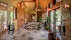 A spacious hallway with wooden doors, a chandelier, and large windows. - Luxurious Hillside Lodge on a Working Wyoming Ranch (Little Jackson Hole)