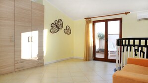 Amplio salón con un gran armario de madera, puerta corrediza de cristal que da a un balcón y un sofá moderno color naranja.