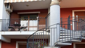 Un edificio de varios pisos con balcón, escaleras y unidad de aire acondicionado.