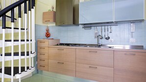 Una cocina con estufa a gas, lavamanos y alacenas.