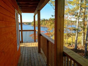 Una terraza de madera con vistas a un lago y follaje otoñal.