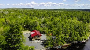Eine Lodge, umgeben von dichtem Wald, mit einem See im Vordergrund.