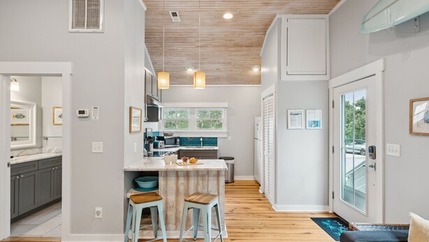 A modern kitchen with a central island, wooden flooring, and pendant lighting. - Stones Throw | Walk to Beach & Center St | 2 Kings + Fenced Yard | Pet Friendly (Folly Beach)