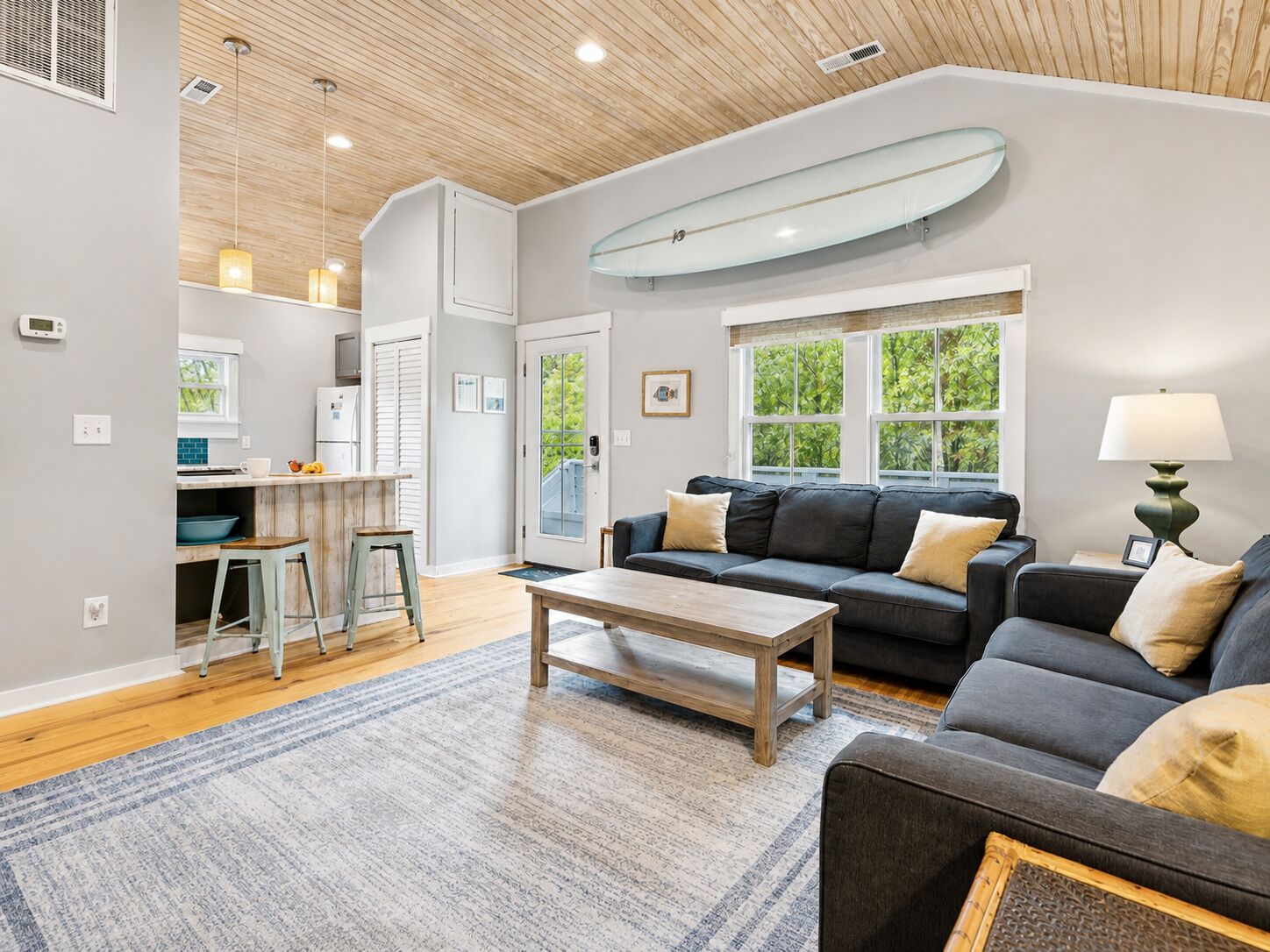 A modern living room with a sofa, coffee table, and a dining area with a kitchen counter.
