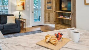 A kitchen with a marble countertop, two croissants, a bowl of mixed berries, and two white coffee mugs. - Stones Throw | Walk to Beach & Center St | 2 Kings + Fenced Yard | Pet Friendly (Folly Beach)