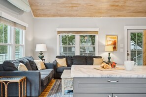 A modern living room with a sofa, a dining table, and a kitchen area.