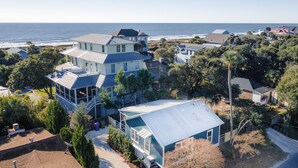 A coastal house with a large deck, a covered porch, and a view of the ocean. - Stones Throw | Walk to Beach & Center St | 2 Kings + Fenced Yard | Pet Friendly (Folly Beach)