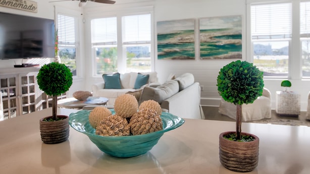 Una sala de estar moderna con un ventanal grande, un sofá y un cuenco color turquesa con objetos decorativos.