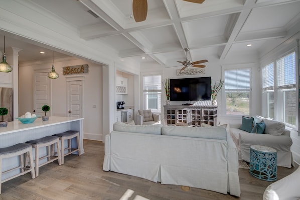 A spacious living area with a sofa, a television, and a kitchen area with a bar.