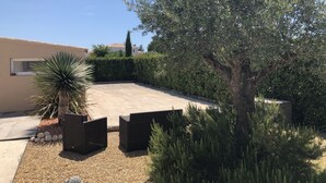 A landscaped outdoor area with a gravel driveway, a large tree, and a building with a window. - Villa overlooking the hill between Hyeres and St Tropez (Solliès-Pont)