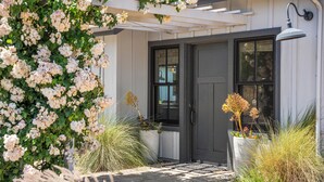 A building entrance with a dark door, a white porch, and a wall-mounted light fixture.