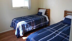 A bedroom with two single beds, a window with white curtains, and a wall-mounted keychain.