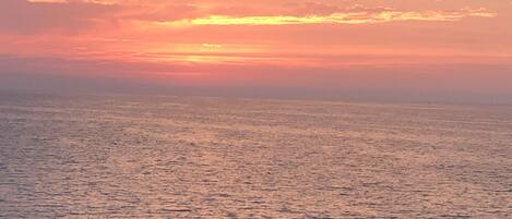 A sunset over a calm sea with a clear horizon.