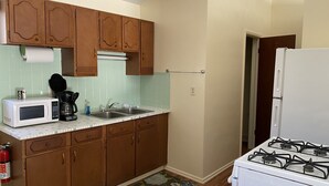 A kitchen with wooden cabinets, a white microwave, a gas stove, and a sink.
