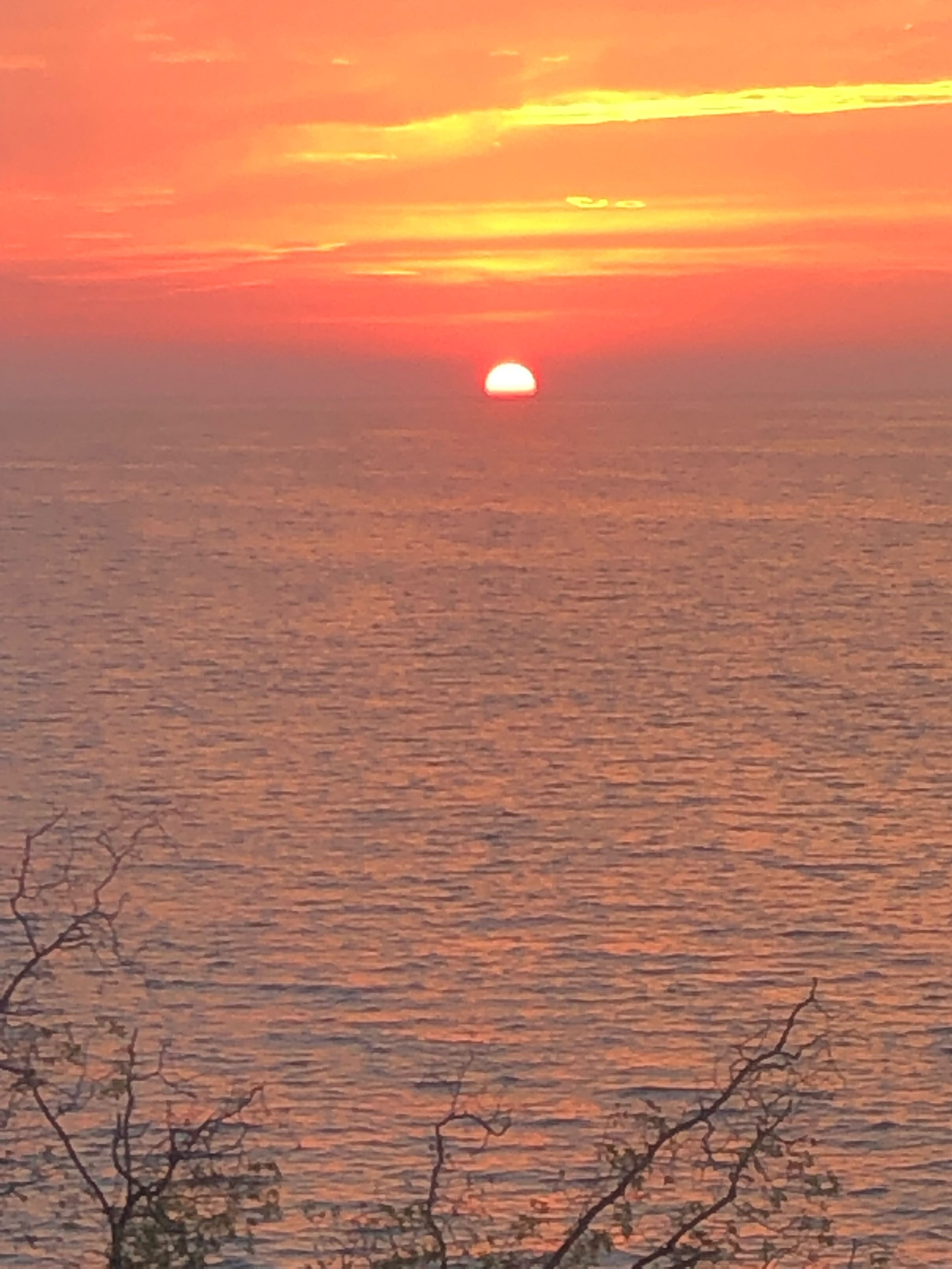 A sunset over a calm sea with a clear horizon.
