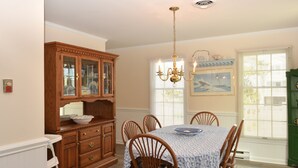 A dining room with a wooden cabinet, a chandelier, and a table set for four. - Fenwick Island Home w/ Ocean Views Sleeps 11 (Fenwick Island)