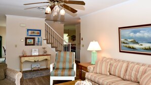 A living room with a ceiling fan, a sofa, a chair, a coffee table, and a painting on the wall. - Fenwick Island Home w/ Ocean Views Sleeps 11 (Fenwick Island)