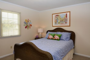 A bedroom with a bed, a nightstand, a lamp, and wall art.