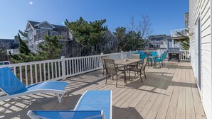 A wooden deck with outdoor furniture, including chairs and a table, surrounded by a white fence. - Fenwick Island Home w/ Ocean Views Sleeps 11 (Fenwick Island)