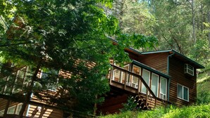 A wooden cabin with a deck, surrounded by dense forest. - "Enchantment"  Medford, Oregon (Medford)