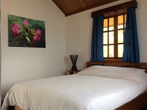 Cozy retreat with a single bed, a window, and a beautiful painting of flowers.