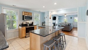 A spacious kitchen with a central island, wooden cabinets, and a large window.