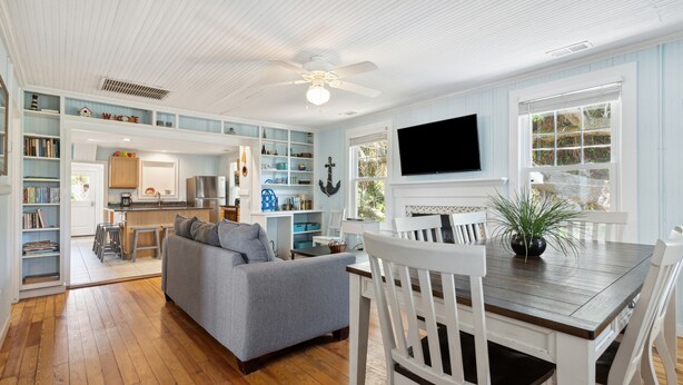 A spacious kitchen with wooden cabinets, a dining area with a table and chairs, and a living room with a sofa.